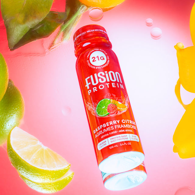 Fusion Protein Raspberry Citrus shot bottle in water with fresh fruit